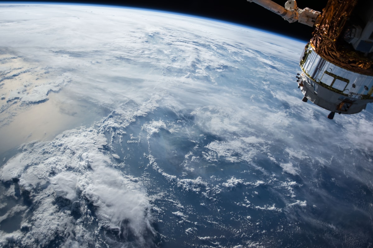 Spacecraft orbiting above Earth blue atmospheric limb